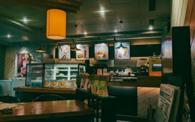 A cozy cafe interior with warm lighting, wooden tables, and menu boards behind the counter.