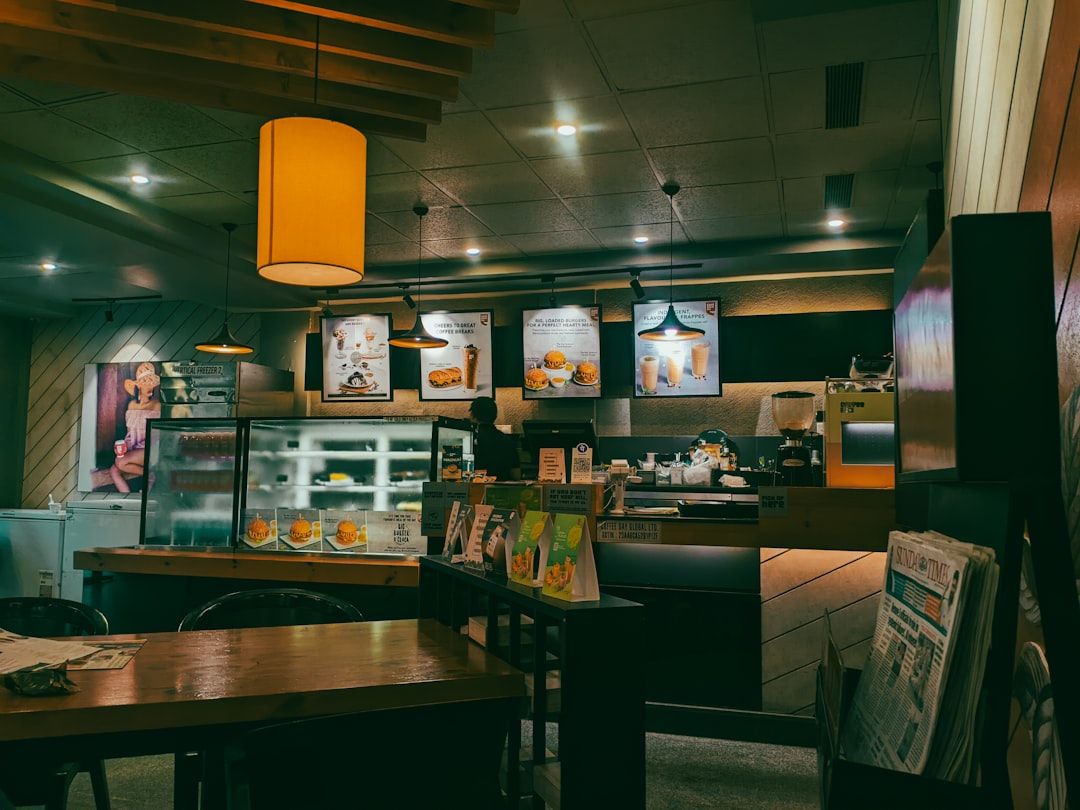 A cozy cafe interior with warm lighting, wooden tables, and menu boards behind the counter.